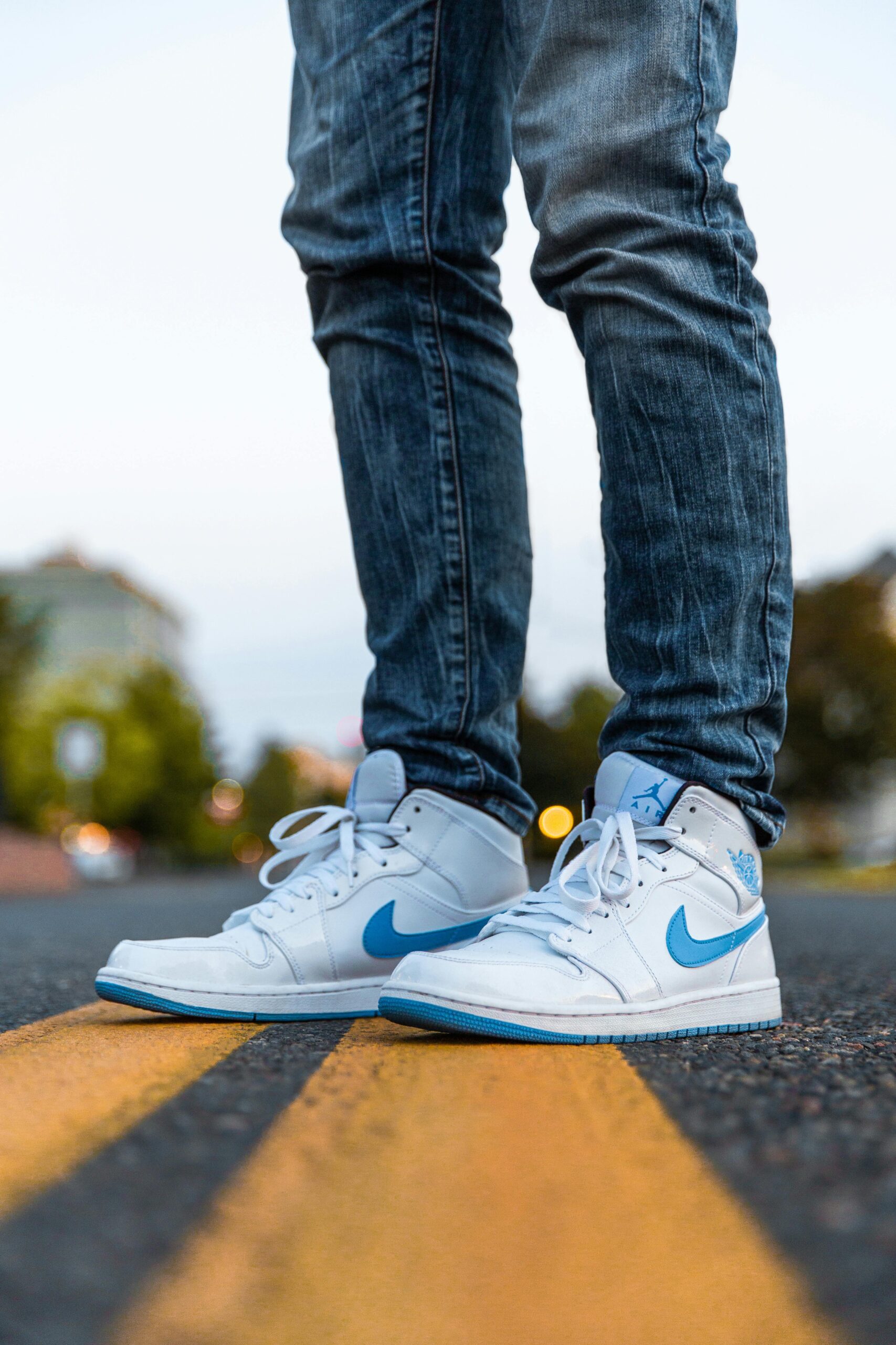 Stylish blue and white sneakers standing on a road with a vibrant urban background.